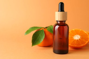 Turuncu arka planda mandalina yağı ve meyveler. Metin için boşluk