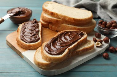 Çikolata ezmeli tost, fındık ve açık mavi ahşap masada bıçak, yakın plan.