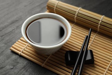 Soya sosu kasede ve çubuklar siyah masada, yakın plan.