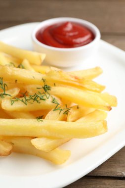 Tahta masada dereotlu ve ketçaplı patates kızartması, yakın plan.