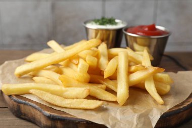 Ahşap masada soslu patates kızartması, yakın plan.