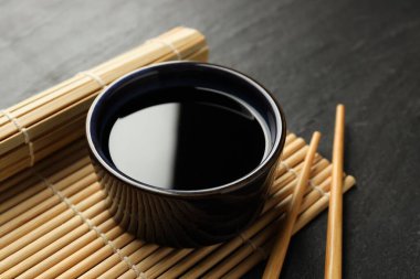 Soya sosu kasede ve çubuklar siyah masada, yakın plan.