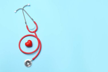 Kan basıncını ölçüyorum. Açık mavi arka planda steteskop ve kalp figürü, üst manzara. Metin için boşluk