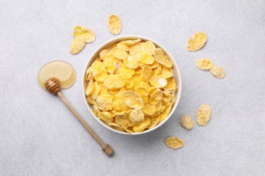 Lezzetli mısır gevrekleri kasede servis edilir bal ile gri masada, düz yatar