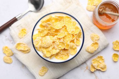 Lezzetli mısır gevrekleri, beyaz mermer masada bal ile servis edilir.