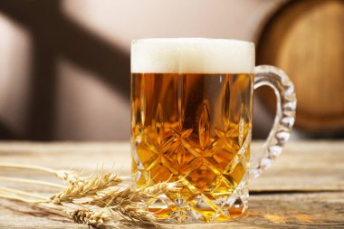 Ahşap masada taze bira, çiviler ve açık gri arka planda fıçı, yakın plan.