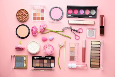Farklı makyaj ürünleri ile bahar kompozisyonu ve pembe arka planda çiçekler, düz yatıyordu