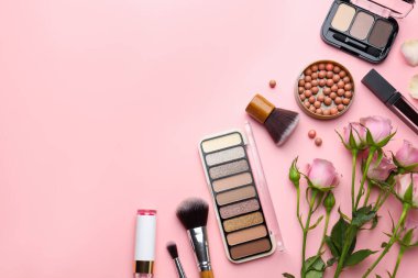 Farklı makyaj ürünleri ve pembe arka planda güzel çiçekler. Metin için boşluk
