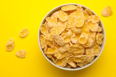 Sarı arka planda kasede lezzetli mısır gevrekleri, üst manzara.