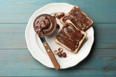 Çikolata ezmeli tost, fındık ve bıçak açık mavi ahşap masa, üst görünüm