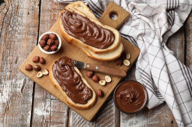 Çikolata ezmeli tostlar, fındıklı fındıklar ve tahta masa üzerinde bıçak, düz uzanma