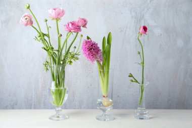 Beyaz masadaki cam vazolarda güzel pembe çiçekler.