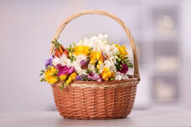 Sepetteki güzel frezya çiçekleri bulanık arka plana karşı ışık masasının üzerinde