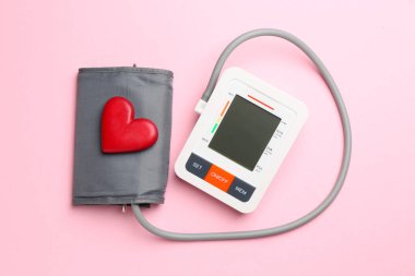 Kan basıncını ölçüyorum. Pembe arka planda Sphygmomanometer ve kırmızı kalp figürü, üst görünüm