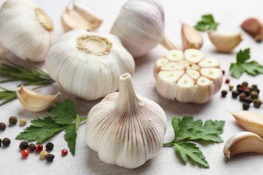 Taze sarımsak, biber, biberiye ve maydanoz açık gri masada, yakın plan.