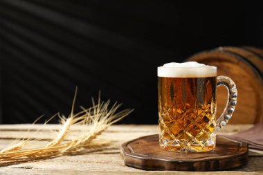 Ahşap masada taze bira, dikenler ve koyu arka planda fıçı, yakın plan.