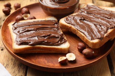 Çikolata ezmeli tostlar ve ahşap masada fındıklar, yakın plan.