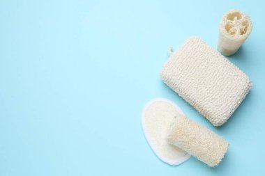 Açık mavi arka planda banyo bezi ve lif süngeri. Metin için boşluk