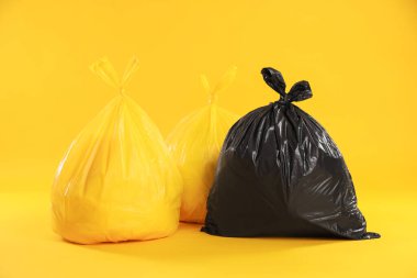 Sarı arka planda renkli poşetlerdeki çöpler