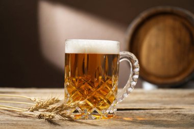 Ahşap masada taze bira, çiviler ve açık gri arka planda fıçı, yakın plan.