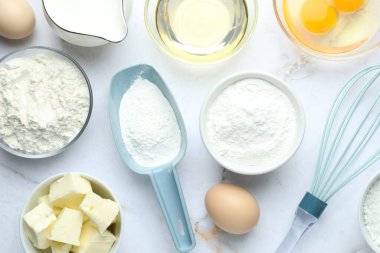 Kabartma tozu ve beyaz mermer sehpada hamur yapmak için diğer malzemeler.