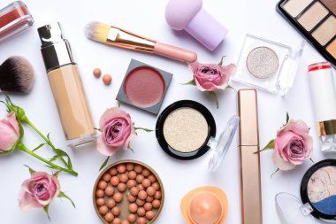 Farklı makyaj ürünleri ve beyaz arka planda pembe güller içeren bahar kompozisyonu