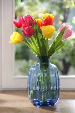 Kapalı kapılar ardında, ahşap masadaki vazodaki güzel bahar çiçekleri.