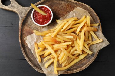 Koyu ahşap masada ketçaplı leziz patates kızartması.