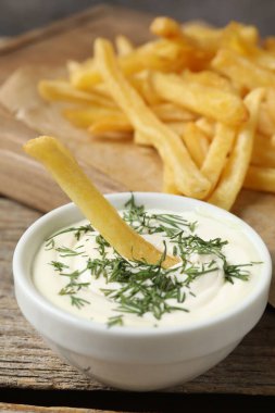 Tahta masada soslu patates kızartması, yakın plan.