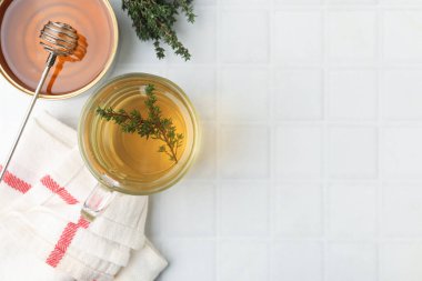 Cam bardakta taze kekik çayı, otlar, peçete ve bal beyaz fayanslı masa, düz yatak. Metin için boşluk