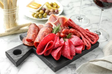 Şarküteri tahtası, farklı pişirilmiş et, sosis ve beyaz mermer masada şarap, yakın plan.