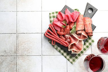 Şarküteri tahtası, farklı pişirilmiş et, sosis ve beyaz fayanslı masada şarap, düz yatak. Metin için boşluk