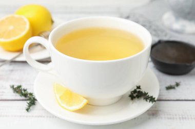 Aromatik kekik çayı bardakta, limon ve bal açık ahşap masada, yakın plan