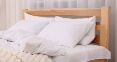 Taze pamuklu çarşaflar ve ekose kumaşlarla rahat bir yatak, yakın plan.