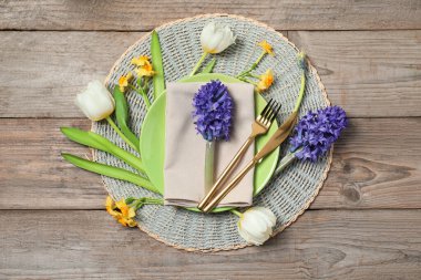 Ahşap arka planda çiçek dekoru olan şık masa ayarları, düz yatış