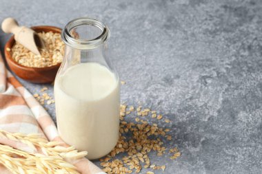 Cam şişede yulaf sütü ve gri desenli masada gevrek, yakın plan. Metin için boşluk