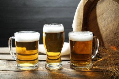 Taze biralı bardaklar, çiviler ve tahta masanın üzerinde koyu arkaplan, yakın plan.
