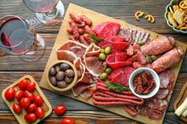 Farklı pişirilmiş et, sosis, domates, zeytin ve şarapla ahşap masa, düzlük.