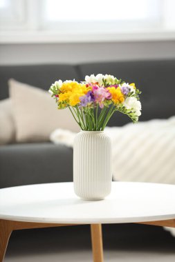 Beyaz masadaki vazodaki güzel frezya çiçekleri.