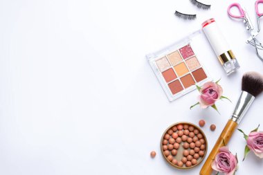 Farklı makyaj ürünleri ve beyaz arka planda pembe güller içeren bahar kompozisyonu. Metin için boşluk