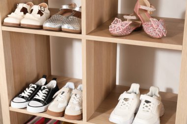 Raf ünitesinde farklı stil çocuk ayakkabıları var. Kapalı, yakın çekim.