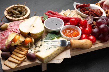 Siyah masada bir sürü aperatif olan şarküteri tahtası, yakın plan.