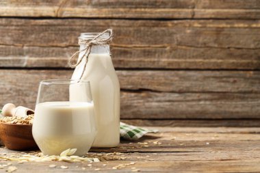 Bardaktaki yulaf sütü, şişe, gevrek ve çiviler ahşap masa, yazı için yer