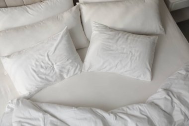 Beyaz yastıklar ve temiz çarşaflar yatağın üstünde.