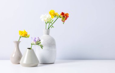 Beyaz masadaki vazoların içinde güzel frezya çiçekleri. Metin için boşluk