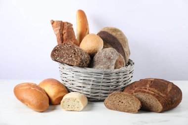 Beyaz mermer masada hasır sepetteki farklı ekmek türleri.