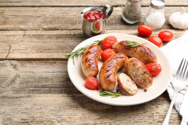 Ahşap masada servis edilen leziz ızgara sosisler, domatesler ve biberiye, yakın plan. Metin için boşluk