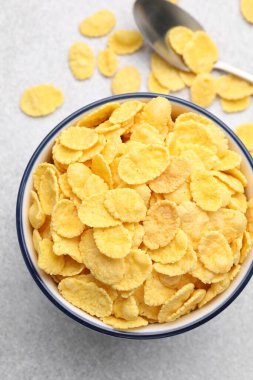 Lezzetli mısır gevreği kasede ve kaşık açık gri masada, düz yatıyordu.