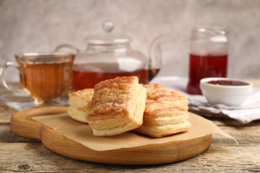 Lezzetli puf börekleri, reçel ve çay ahşap masada, yakın plan.