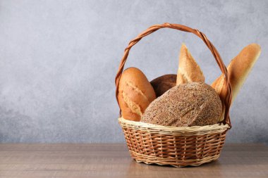Hasır sepetin içinde, ahşap masanın üzerinde farklı ekmek türleri, yakın plan. Metin için boşluk